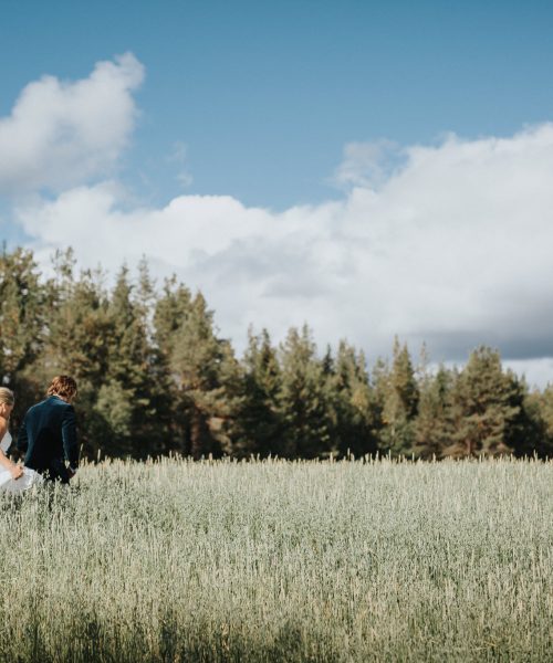 Brudpar går över fält under sitt bröllop i Funäsfjällen